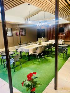 a dining room with tables and chairs and green carpet at Maun East Gate Guesthouse in Maun