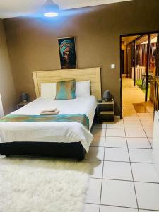 a bedroom with a large bed and a tiled floor at Maun East Gate Guesthouse in Maun