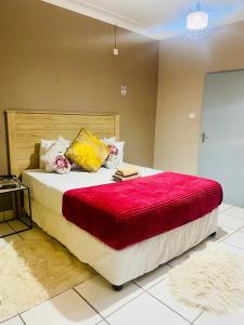 a bedroom with a large bed with a red blanket at Maun East Gate Guesthouse in Maun