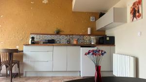 a kitchen with white cabinets and a vase with flowers at Gîte La Thibaud in Lavernat