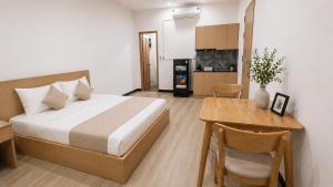 a bedroom with a bed and a table and a kitchen at Lemon Hotel & Apartment in Danang +5 photos