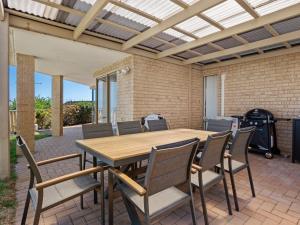 a patio with a wooden table and chairs at Ocean Reef Marina by the Sea 4BR plus Study plus in Perth