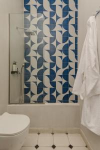 a bathroom with a toilet and a blue and white shower curtain at Oikia Classic House in Old Town Kavala in Kavála +32 photos
