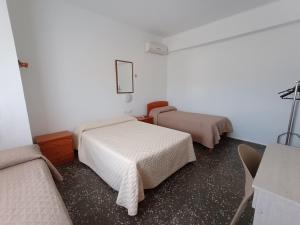 a room with two beds and a table with a lamp at Pensíon Lucia in Casinos