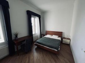 a bedroom with a bed and a desk and two windows at Spacious 2 bedroom apartment, Old Town Riga in Riga
