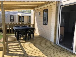 a patio with a table and chairs on a deck at Camping 3 étoiles - 1km de la plage - Piscine chauffée et Espace Fitness in Saint-Georges-de-Didonne