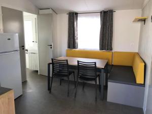 a kitchen with a table and chairs and a refrigerator at Camping 3 étoiles - 1km de la plage - Piscine chauffée et Espace Fitness in Saint-Georges-de-Didonne +118 photos