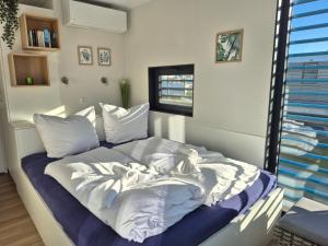 a bedroom with a bed with white sheets and a window at Floatinghouse Marama - LP10 in Peenemünde
