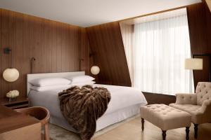 a bedroom with a large white bed and a chair at The London EDITION in London +115 photos