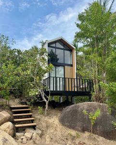 a tree house with a black deck and windows at Duplex House in Chaloklum