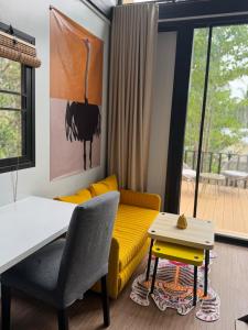 a living room with a yellow couch and a table at Duplex House in Chaloklum