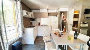 a white kitchen with a table and a table and chairs at ZEcamping 2 avec piscine restaurant vue sur le village de Saint Auban in Briançonnet
