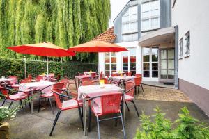 a restaurant with red chairs and tables with umbrellas at Hotel Rennschuh in Göttingen
