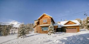 Twin Lift Lodge في Big Sky Mountain Village: كابينة خشب في الثلج مع جبل