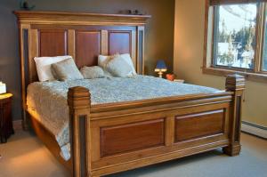 a large wooden bed in a bedroom with a window at Twin Lift Lodge in Big Sky Mountain Village