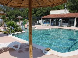a large swimming pool with an umbrella and a chair at ZEcamping 3 étoiles à 4km de la plage piscine chiens acceptés jacuzzi in Bormes-les-Mimosas