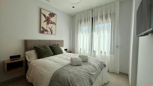 a white bedroom with a large bed and a window at El Puente de Sansueña in Córdoba