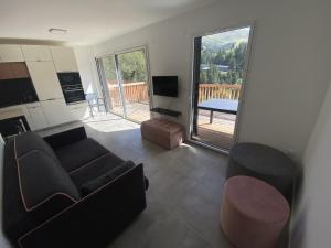a living room with a couch and a television and a balcony at Duplex 3 chambres Etoile du sud in Le Lioran