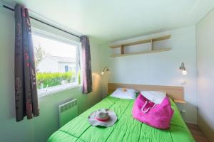 a green bed with a pink bag and a window at ZEcamping 3 étoiles animaux acceptés avec piscine chauffée à Guérande in Guérande