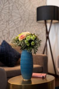 a blue vase with flowers sitting on a table at Luxury Boutique Hotel Iris Porsche in Mondsee +42 photos