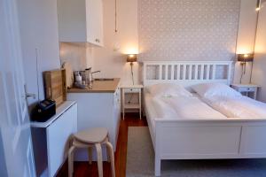 a bedroom with a white bed and a small kitchen at Ferienwohnung LOTTTALEBEN 2 in Timmendorfer Strand
