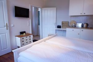 a white bedroom with a bed and a kitchen at Ferienwohnung LOTTTALEBEN 2 in Timmendorfer Strand