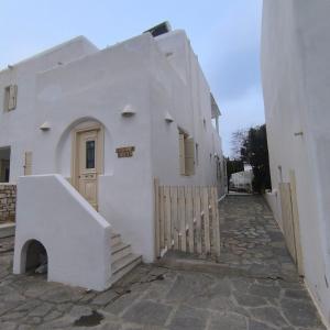 a white building with a gate and a door at Theros Casa Logaras in Piso Livadi