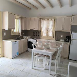 a kitchen with a white table and white appliances at Theros Casa Logaras in Piso Livadi