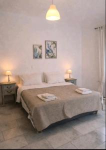 a white bedroom with a large bed with two tables at Theros Casa Logaras in Piso Livadi