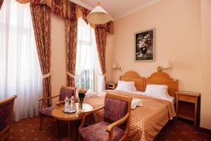 a hotel room with a bed and a table and chairs at Hotel Pavlov in Karlovy Vary