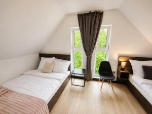 a bedroom with two beds and a chair and two windows at VeloDomki Żywiec - domki nad Jeziorem Żywieckim in Żywiec
