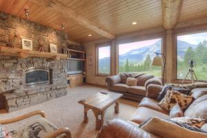 a living room with couches and a stone fireplace at Lone View Lodge in Big Sky Mountain Village