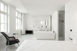 ein weißes Badezimmer mit weißer Badewanne und einem Stuhl in der Unterkunft Zenden Hotel Maastricht in Maastricht + 30 Fotos