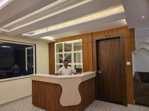 a man sitting at a counter in a room at Hotel Gangotri Suites in Haridwār