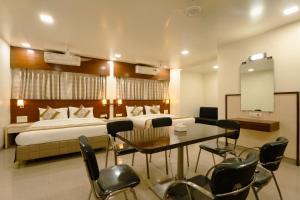 a hotel room with a bed and a table and chairs at Hotel Sitara Residency in Navi Mumbai