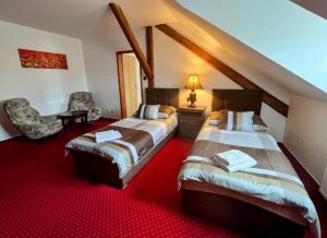 zwei Betten in einem Zimmer mit rotem Teppich in der Unterkunft Hotel Fogl in Nová Bystřice