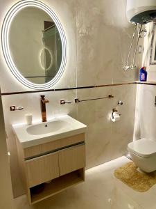 a bathroom with a sink and a mirror and a toilet at Luxurious apartment in New cairo