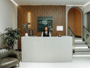 a woman standing behind a counter in a lobby at NOOMA Hotel Frunze in Bishkek