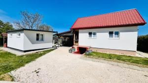 a white house with a red roof at Lebegő Falu Vendégház in Oroszlány