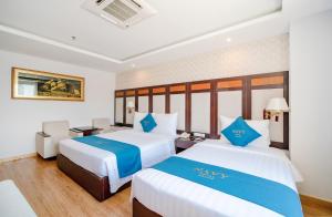 two beds in a hotel room with blue and white at Galliot Hotel Nha Trang in Nha Trang