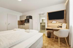 a white room with a bed and a desk and a television at Colleen Apartments Wesertal in Porta Westfalica