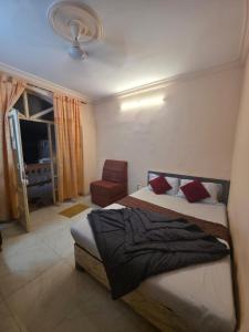 a bedroom with a bed and a chair in it at The Wayside Inn in Matheran
