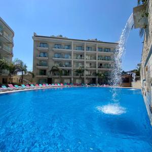 a swimming pool with a fountain in front of a hotel at Sunshine Resort - Tabarja, Lebanon in An Nā‘ūrah