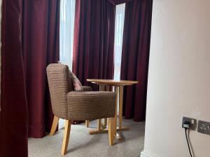 a chair and a table in a room with curtains at Blaby Westfield Hotel in Blaby
