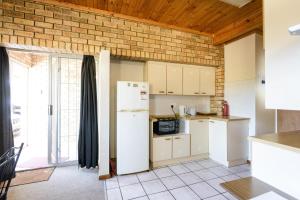 a kitchen with white appliances and a brick wall at Albatross Beach Guest House in Jeffreys Bay