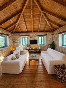 a living room with white couches and a wooden ceiling at Light & Stone Villa, Kefalonia in Lixouri