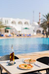 two plates of food on a table next to a pool at Hotel Bougainvillier Djerba in Taguermess