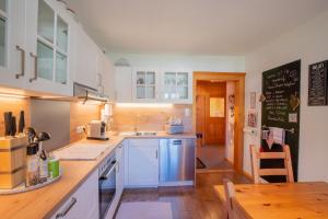 a kitchen with white cabinets and a table and a blackboard at Haus Berta, Montafon in Partenen