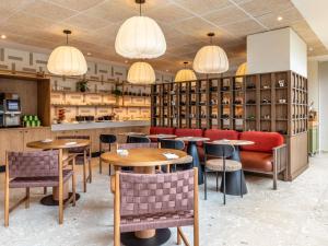 a restaurant with tables and chairs and lamps at Hôtel Mercure Paris Boulogne Pont de Saint Cloud in Boulogne-Billancourt