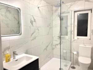 a white bathroom with a sink and a shower at Bay Breeze Hideaway in Cobh